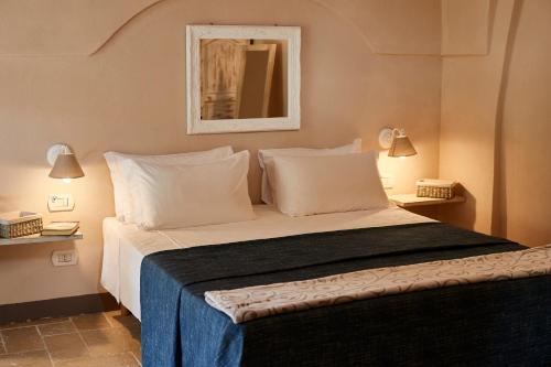 a bedroom with a bed with white pillows and a mirror at Borgo San Gaetano in Bernalda