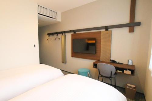 a bedroom with two beds and a desk and a television at Hotel The M's Kyoto in Kyoto