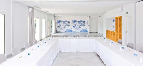 a large white room with white tables and chairs at Hôtel Les Grenettes in Sainte-Marie-de-Ré