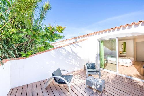 - une terrasse avec 2 chaises et un lit dans une maison dans l'établissement Hôtel Les Grenettes, à Sainte-Marie de Ré