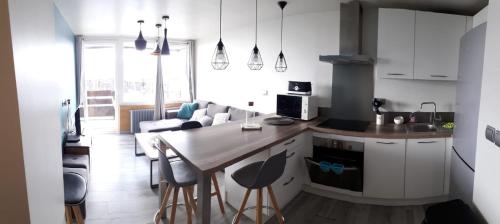 a kitchen with white cabinets and a table with bar stools at Appartement 39 m, 2 pièces, départ, retour ski à 150 m, belle vue in Tignes