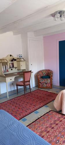 a room with a desk and a chair and a rug at Le Clos Marie in Brénod