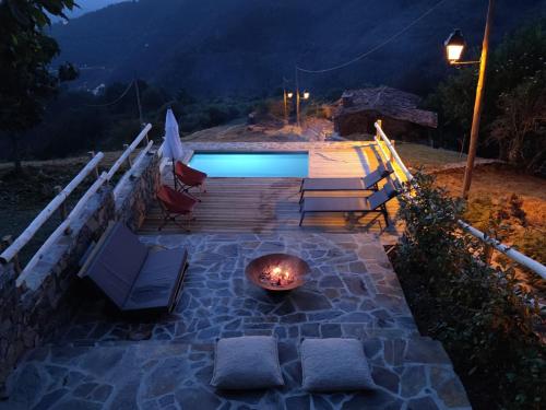 a patio with a fire pit and a pool at night at Casa do Ti Tóte in Talasnal