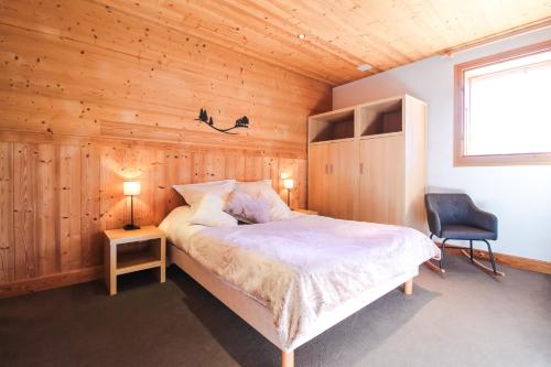 a bedroom with a bed and a chair and a window at Vue panoramique sur les montagnes plein Sud - T2 Skis aux pieds, Piscine, Jacuzzi in Flaine