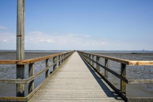 a wooden pier stretches out into the ocean at Butjadinger Hof in Burhave