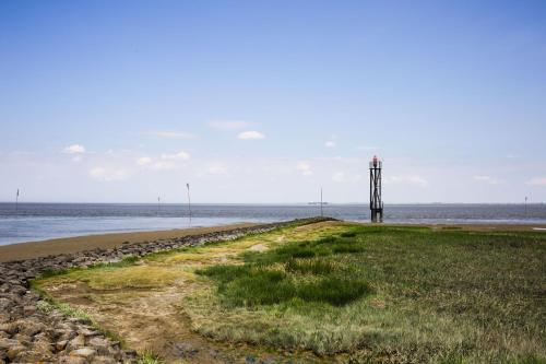a lighthouse on a beach next to the water at Butjadinger Hof in Burhave