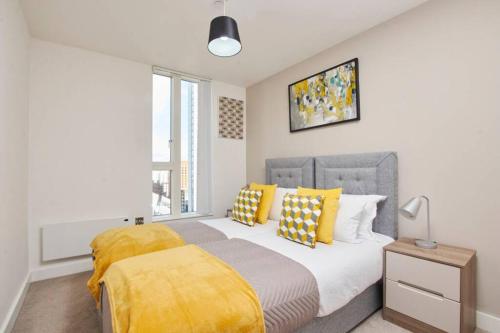 um quarto com uma cama grande e almofadas amarelas em Lovely Apartment - Private Parking - Stadium Views em Manchester