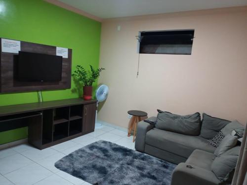 a living room with a couch and a flat screen tv at Casa com Ar e piscina no centro in Prado