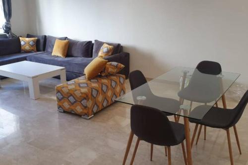 Apartment Near & close to Casablanca Mohammed V International Airport في نواصير: غرفة معيشة مع طاولة زجاجية وأريكة