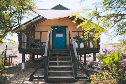 a tiny house with a blue door and stairs at Boker Valley Farm in Sede Boqer