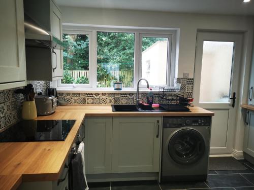 a kitchen with a sink and a washing machine at Tenby Flat in Pembrokeshire