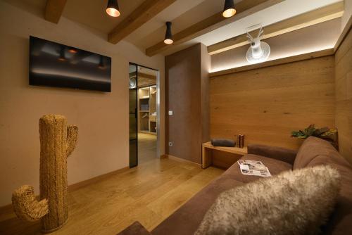 a living room with a couch and a tv on the wall at Hotel Compagnoni in Livigno