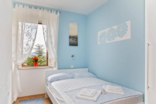 a blue bedroom with a bed and a window at Gardenia House in Janjina