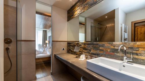 a bathroom with a sink and a mirror at Romantik Hotel Santer in Dobbiaco