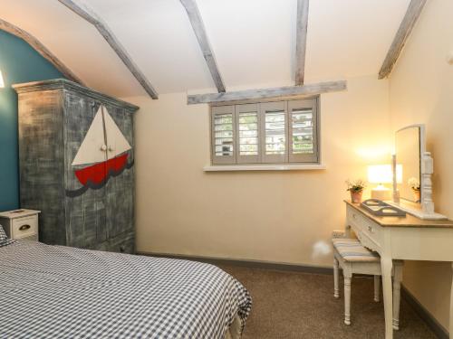 a bedroom with a bed and a desk and a window at Pear Tree Cottage in Mark