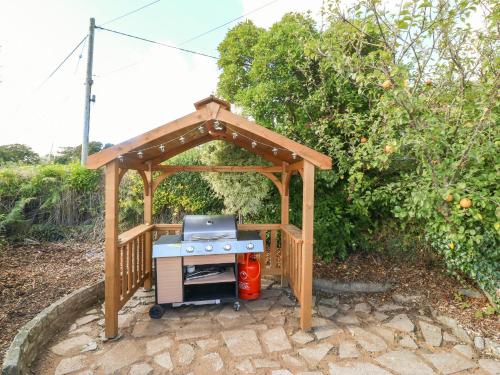 a barbecue under a wooden gazebo at Tan Yr Allt in Pwllheli