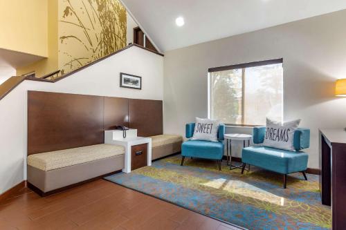 een kamer met een bed en twee blauwe stoelen bij Sleep Inn Henderson I-85 in Henderson