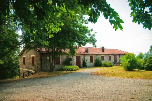 an old stone house with a tree and a driveway at Villaggio Della Salute Più in Monterenzio
