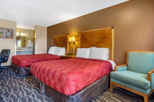 a hotel room with two beds and a chair at Econo Lodge Ellensburg Near University in Ellensburg