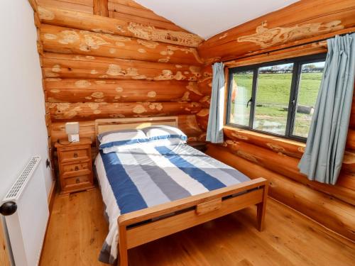 a bedroom with a bed in a log cabin at Douglas Cabin in Worcester