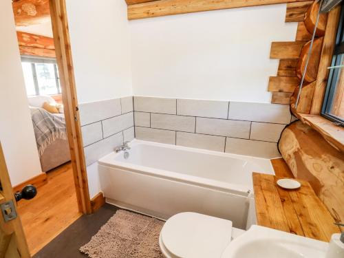 a bathroom with a white tub and a toilet at Douglas Cabin in Worcester