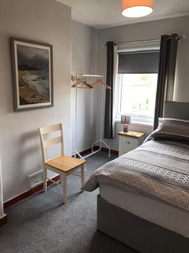 a bedroom with a bed and a chair and a window at The Avenue in Eyemouth