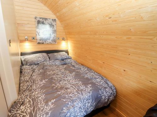 a bed in a room with a wooden wall at Gander Pod in Worcester