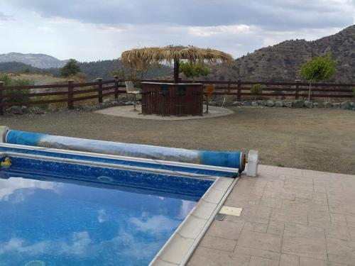 a blue swimming pool with an umbrella in a yard at Kalamospito Holiday House in Kalokhorio