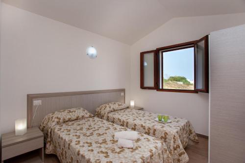 ein kleines Schlafzimmer mit 2 Betten und einem Fenster in der Unterkunft Diana 4 in Budoni