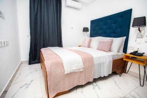 a bedroom with a large bed with a blue headboard at Mica Apartments in Sere Kunda