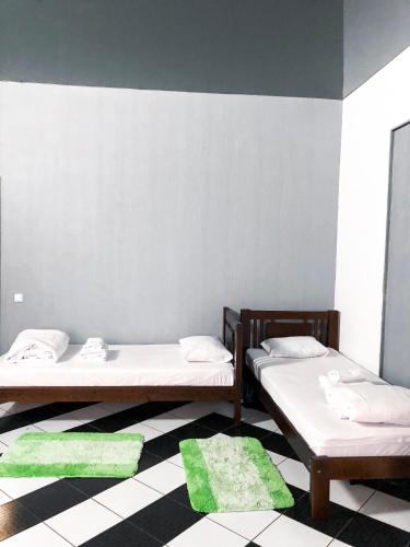 two beds in a room with green mats on the floor at Hotel Zipper House in Odesa