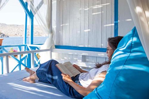 a woman laying on a bed reading a book at Aphrodite Hotel Bozburun in Bozburun