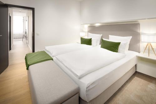 um quarto com uma grande cama branca com almofadas verdes em Bergmann Boardinghouse Oldenburg em Oldenburg