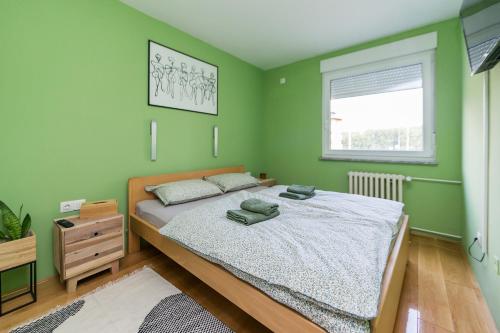 a green bedroom with a bed and a window at Apartman Bruna SELF CHECK-IN in Osijek