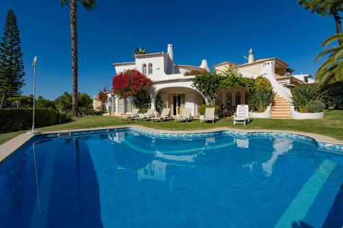 a villa with a swimming pool in front of a house at Casa de Gales - Vilamoura in Vilamoura