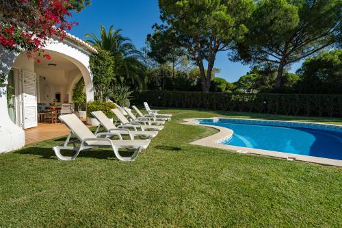 a row of lounge chairs next to a swimming pool at Casa de Gales - Vilamoura in Vilamoura