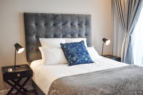 a bedroom with a large bed with a blue pillow on it at Red Velvet - Lux One Bedroom in Pretoria
