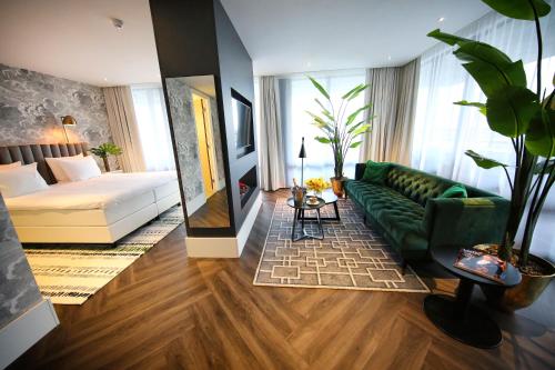 a living room with a green couch and a bed at Van der Valk Hotel Den Haag in Nootdorp