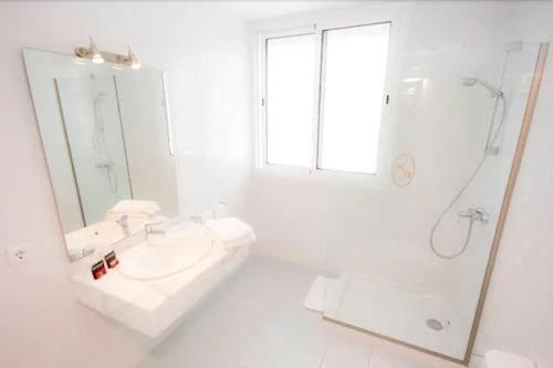 uma casa de banho branca com um lavatório e um chuveiro em Hotel Morito em Cala Millor