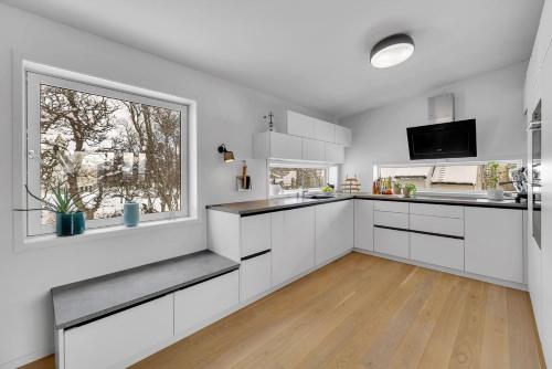 a kitchen with white cabinets and a window at Kais sauna, jacuzzi, cinema and balcony house! Central location in Tromsø