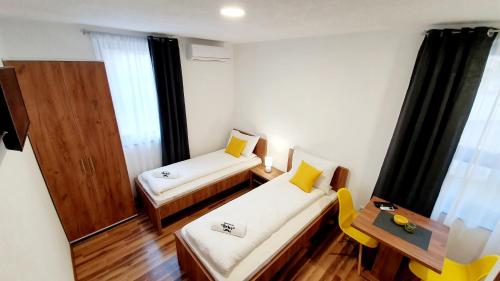 Habitación pequeña con 2 camas y mesa. en Apartmani Brko, en Kotor-Varoš