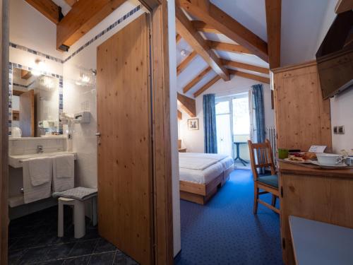 a bedroom with a bed and a bathroom with a sink at Hotel Garni Sottobosco in Dimaro