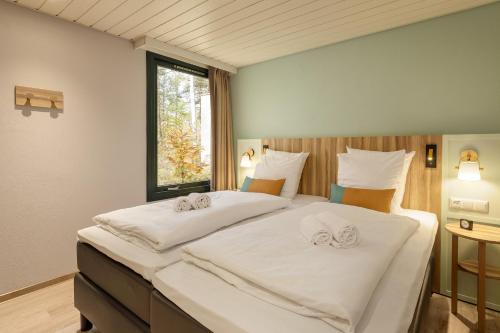 a bedroom with two beds with white sheets and a window at Center Parcs Bispinger Lüneburger Heide in Bispingen