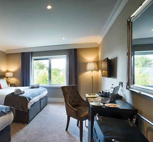 a hotel room with a bed and a desk with a computer at The Village Hotel, Bar and Restaurant in Bettystown