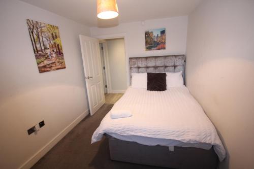 a bedroom with a large bed with white sheets at Holden Court Apartments - Apt 3 in West Drayton