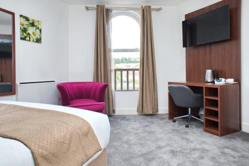 a hotel room with a bed and a desk and a television at Trivelles Rochester Hotel in Rochester