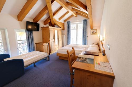 Zimmer mit 2 Betten und einem Schreibtisch in einem Zimmer in der Unterkunft Hotel Garni Sottobosco in Dimaro