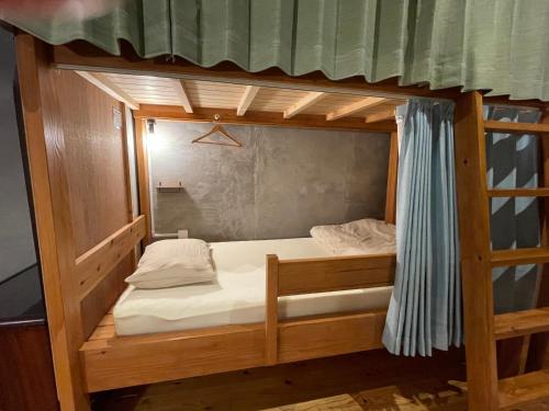 a bunk bed with white sheets and a mirror at Nawate Guesthouse in Matsumoto