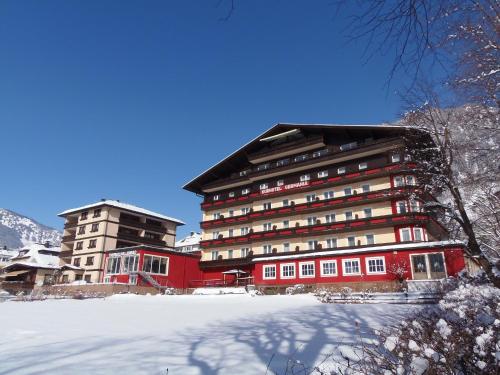 a large red building with snow in front of it at Hotel Germania Gastein - ganzjährig inklusive Alpentherme Gastein in Bad Hofgastein