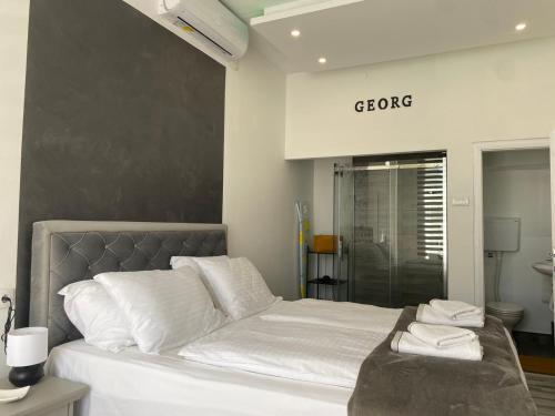 a bedroom with a bed with white sheets and a shower at Apartman Georg in Zrenjanin